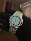 Luxury men’s silver watch with blue dial, showcased on a gloved hand, premium timepiece