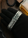 Stainless steel men's watch bracelet held by black-gloved hand, luxury accessory