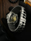 Close-up of a luxury men's automatic watch with visible movement, silver metal band, modern design