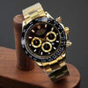 Luxury men's gold chronograph watch with black dial and gold accents on display stand